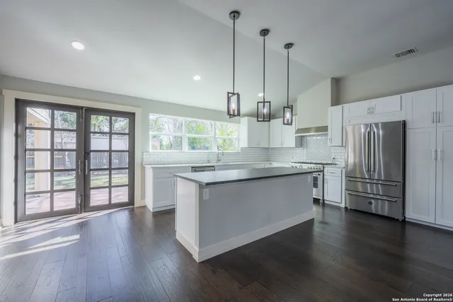 a kitchen with stainless steel appliances granite countertop a refrigerator a stove and a wooden floors