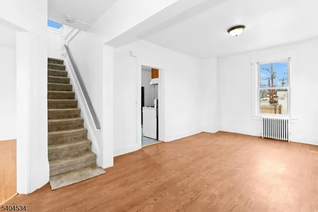 a view of an empty room with wooden floor and stairs
