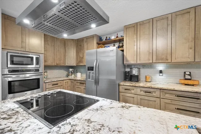 a kitchen with stainless steel appliances granite countertop a sink a stove and refrigerator