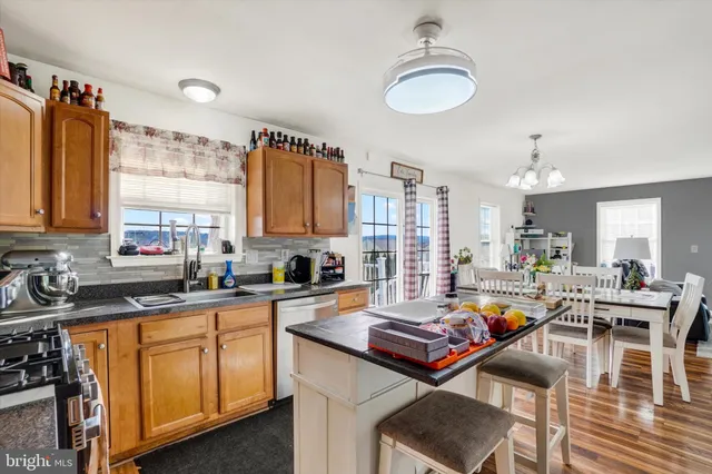 a kitchen with a stove a sink dishwasher and a dining table with wooden floor