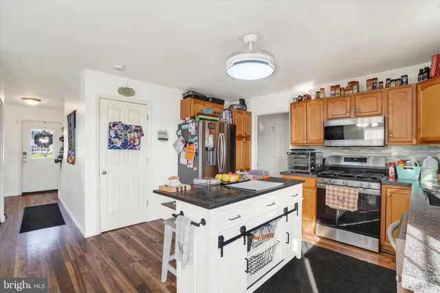 a kitchen with stainless steel appliances a stove top oven a sink a refrigerator and wooden floor