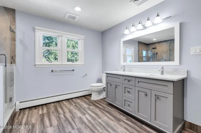 a spacious bathroom with a double vanity sink a mirror and a toilet