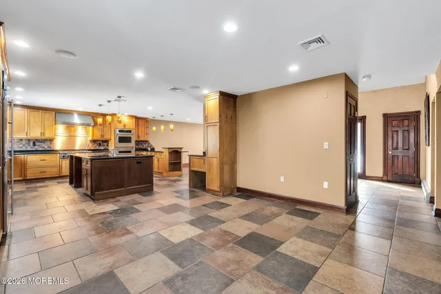 a large kitchen with stainless steel appliances kitchen island granite countertop a refrigerator and a sink