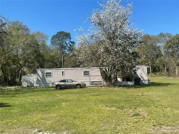 a front view of a house with a garden and trees