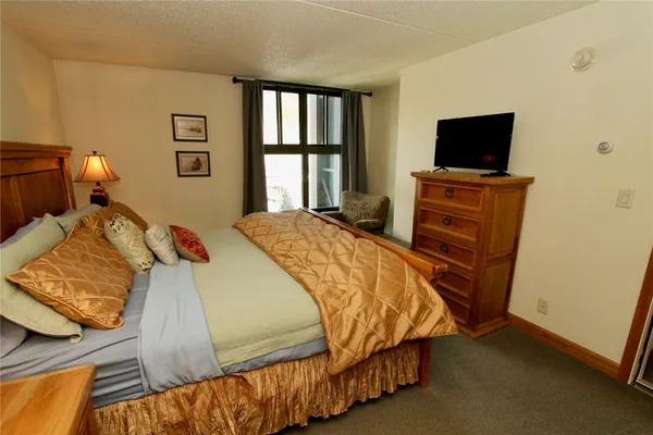 a bedroom with a bed television on desk and a window