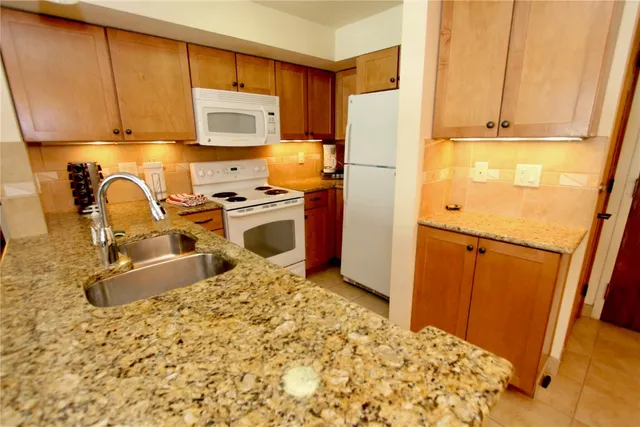 a kitchen with granite countertop a refrigerator and a stove top oven