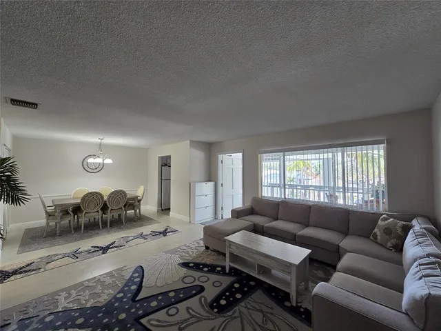 a living room with furniture a large window and a potted plant