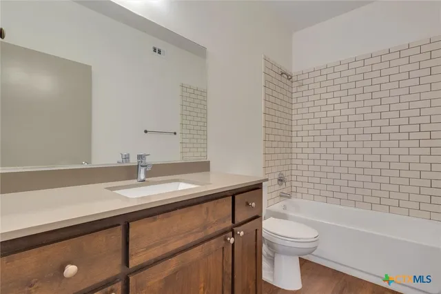 a bathroom with a granite countertop toilet a sink a mirror and bathtub