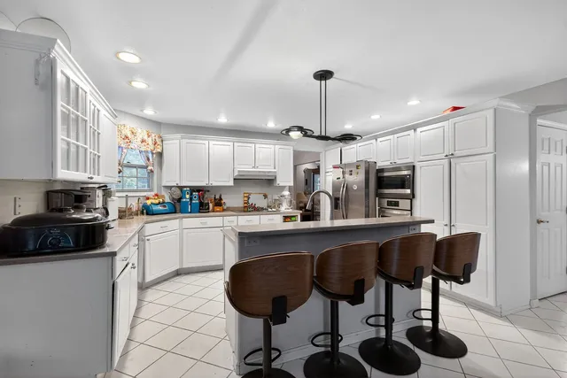 a kitchen with stainless steel appliances granite countertop a sink a stove a refrigerator and chairs
