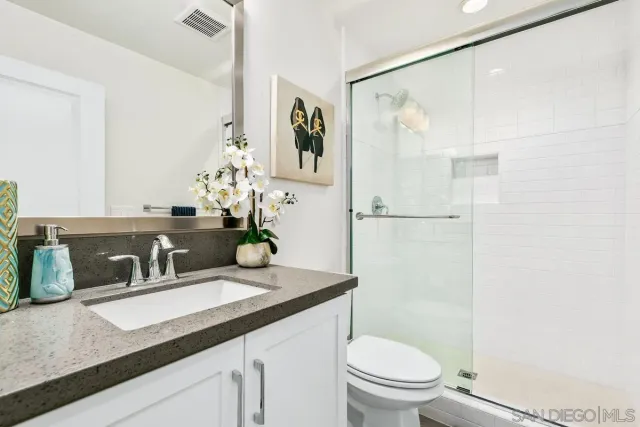 a bathroom with a granite countertop sink a toilet and shower