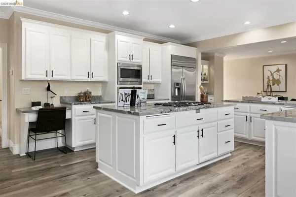 a kitchen with stainless steel appliances granite countertop a stove a sink and white cabinets