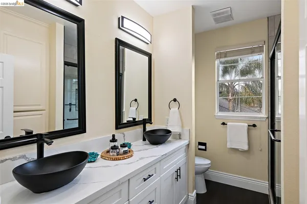 a bathroom with double vanity sinks a toilet a mirror and shower