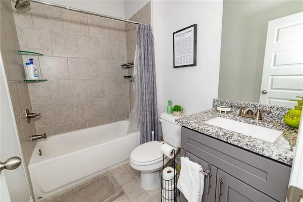 a bathroom with a granite countertop sink toilet a mirror and shower
