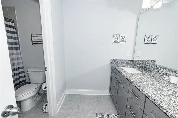 a bathroom with a granite countertop toilet and a sink