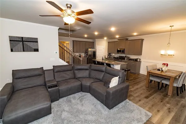 a living room with furniture kitchen view and a wooden floor