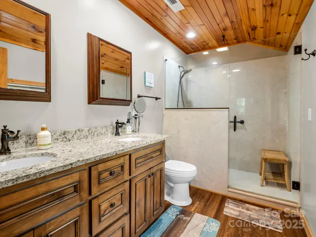 a bathroom with a granite countertop sink a toilet a mirror and shower