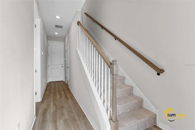 a view of staircase with wooden floor and white walls