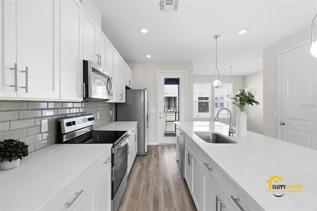 a kitchen with stainless steel appliances a sink a stove a refrigerator a center island and a counter space