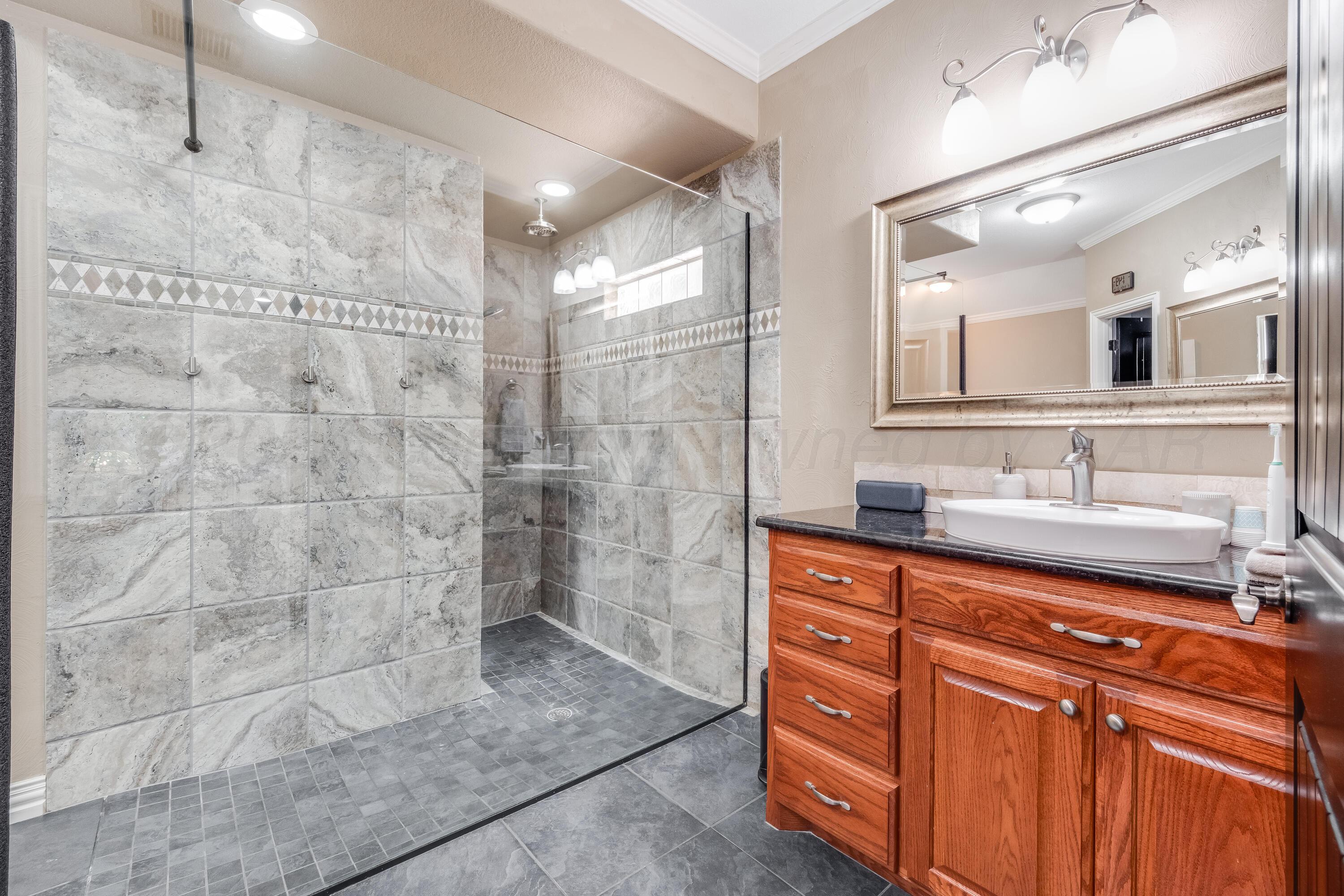 8413 Hamilton Drive Amarillo, TX 79119 - Photo 22 of 54 a bathroom with a granite countertop sink a mirror and shower