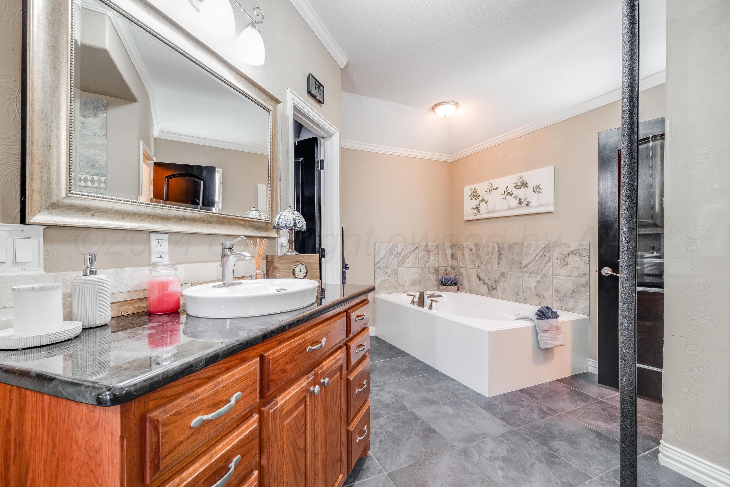8413 Hamilton Drive Amarillo, TX 79119 - Photo 23 of 54 a bathroom with a granite countertop sink a large mirror and a bathtub