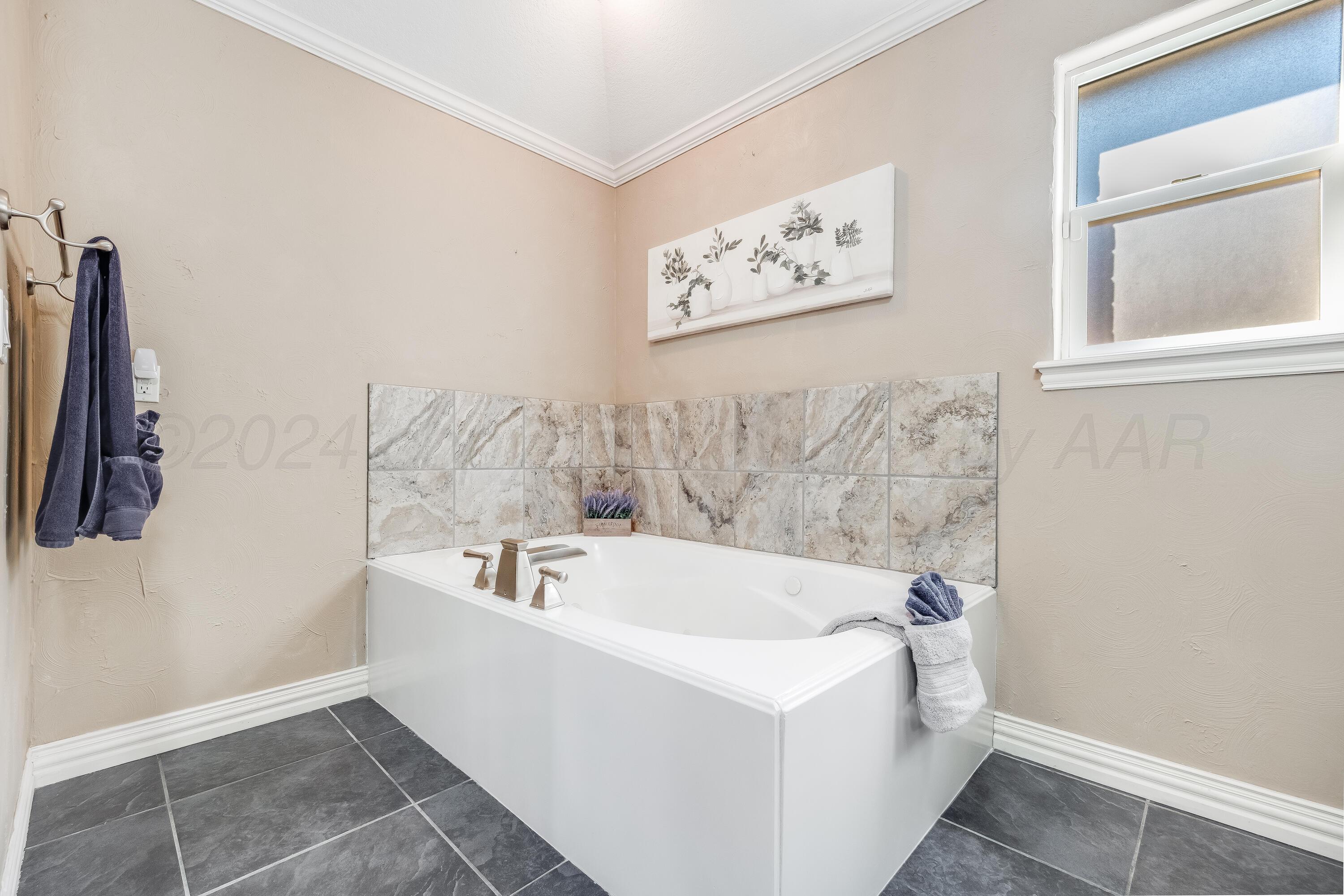 8413 Hamilton Drive Amarillo, TX 79119 - Photo 26 of 54 a bathroom with a bathtub and a window