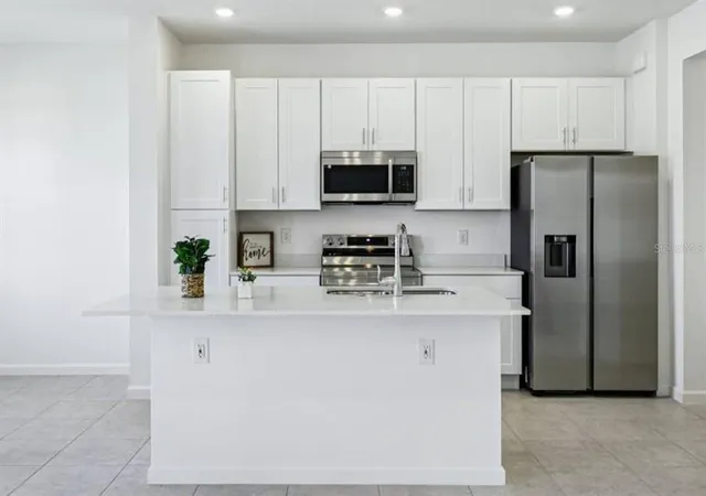 a kitchen with stainless steel appliances granite countertop a refrigerator a stove a sink and a microwave