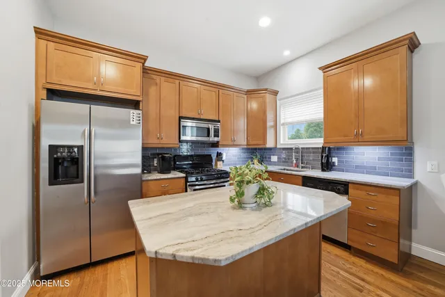 a kitchen with a refrigerator a sink a stove cabinets and living room view