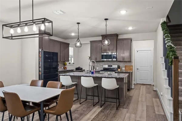 a kitchen with a dining table chairs stainless steel appliances and cabinets