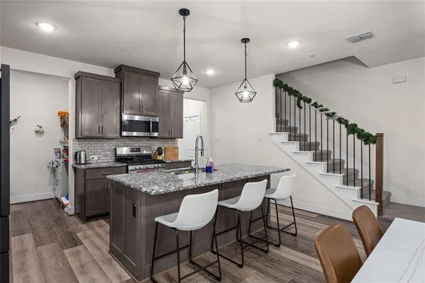 a kitchen with stainless steel appliances kitchen island granite countertop a table chairs and a refrigerator