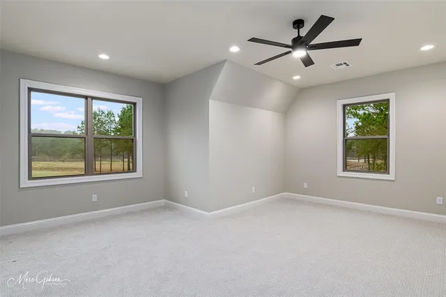 an empty room with windows and fan
