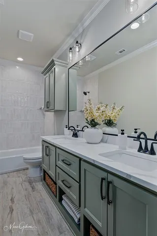a bathroom with a double vanity sink a large mirror and bathtub