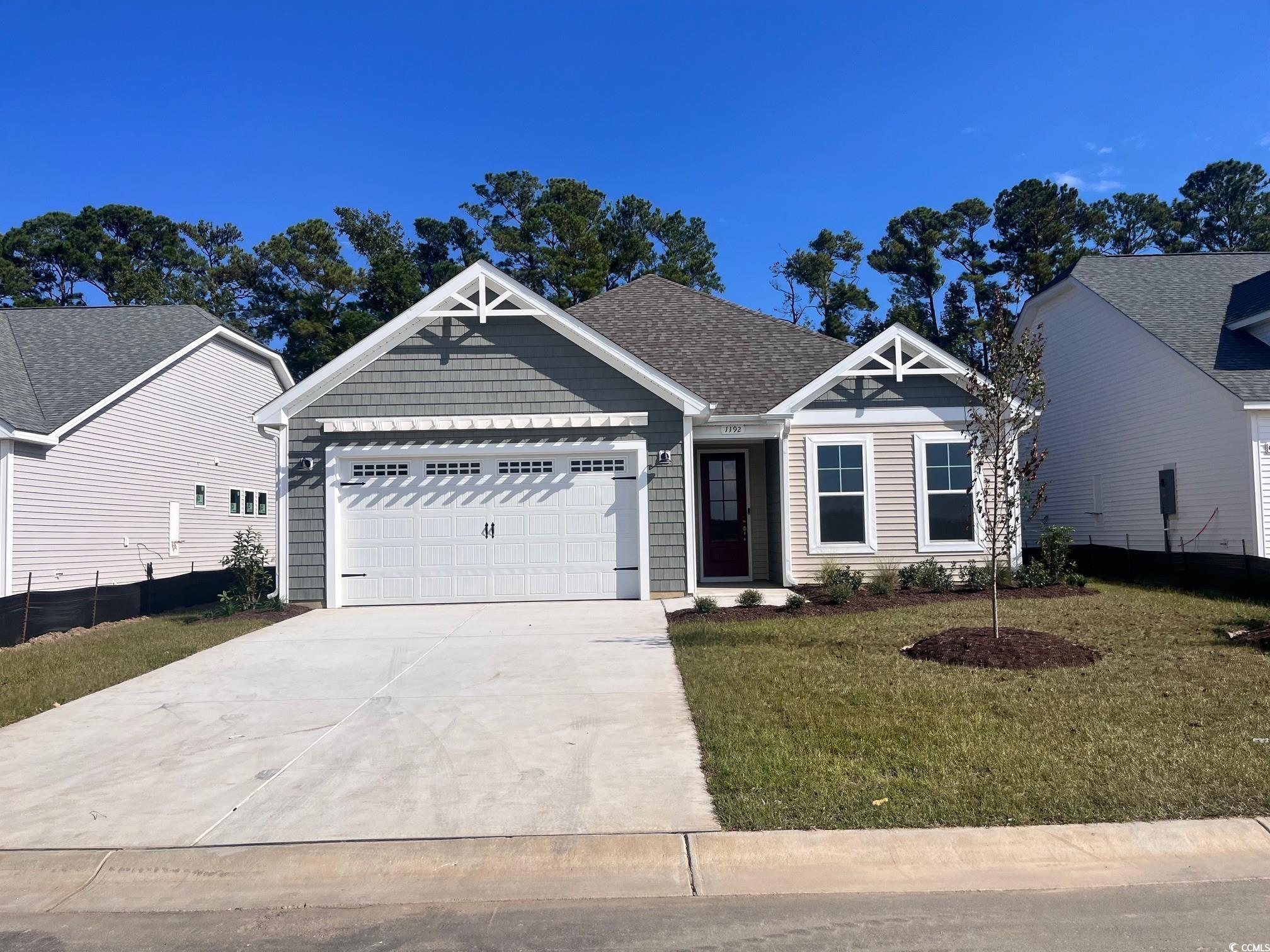 1192 Halter Place Calabash, NC 28467 - Photo 1 of 1 View of front of home featuring concrete driveway, a front lawn, a garage, and roof with shingles