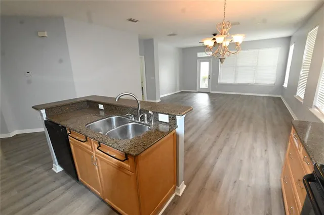 a kitchen with stainless steel appliances granite countertop a sink a stove and a wooden floors