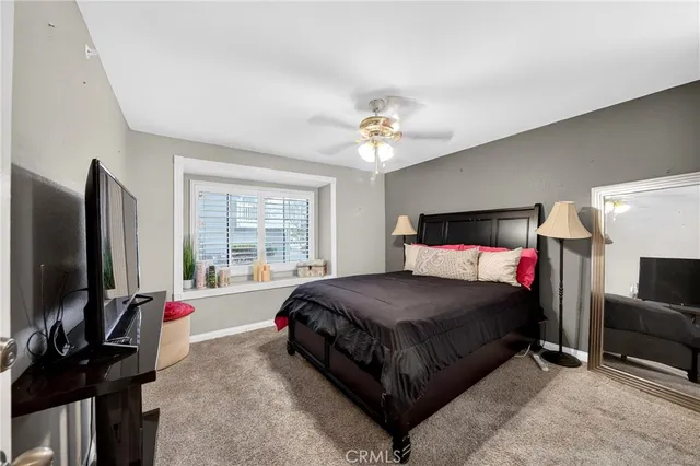 a bedroom with a bed flat screen tv and a large window