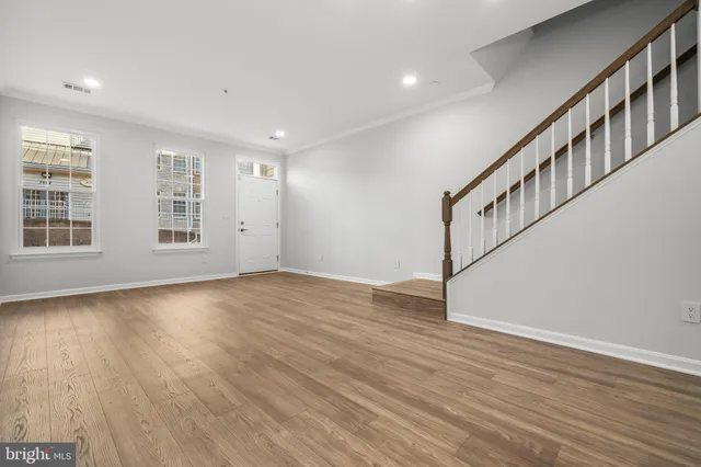 a view of an empty room with wooden floor and windows