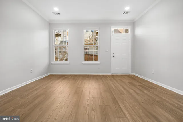 an empty room with wooden floor and windows
