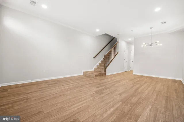 an empty room with wooden floor and staircase