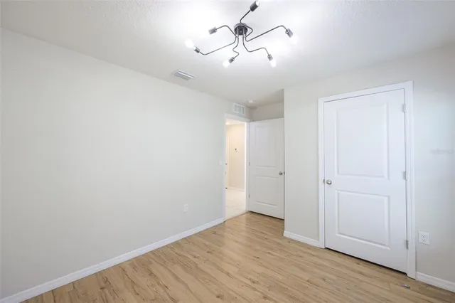 a view of empty room with wooden floor and ceiling fan