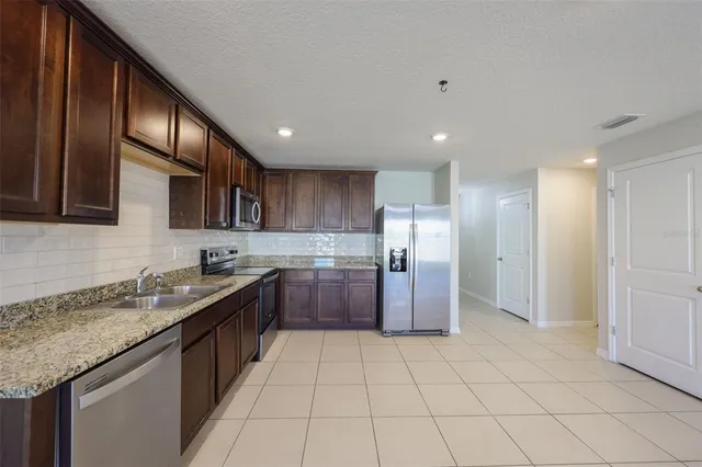a kitchen with stainless steel appliances granite countertop a sink a stove a refrigerator and cabinets