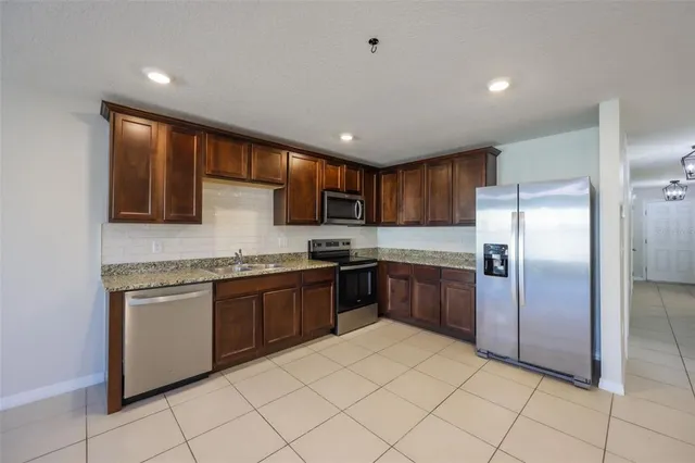 a large kitchen with stainless steel appliances granite countertop a stove top oven a sink dishwasher and a refrigerator