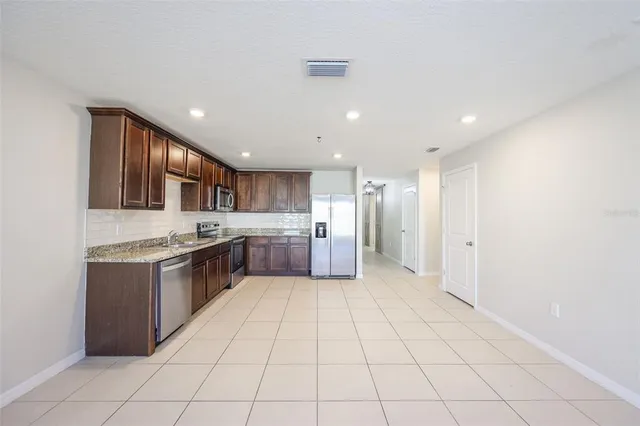 a large kitchen with a large counter top space a sink stainless steel appliances and cabinets
