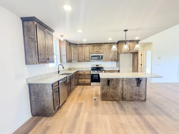 a large kitchen with stainless steel appliances kitchen island granite countertop a stove a sink a refrigerator and a microwave