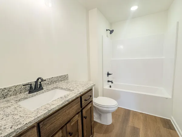 a bathroom with a granite countertop sink a toilet and shower