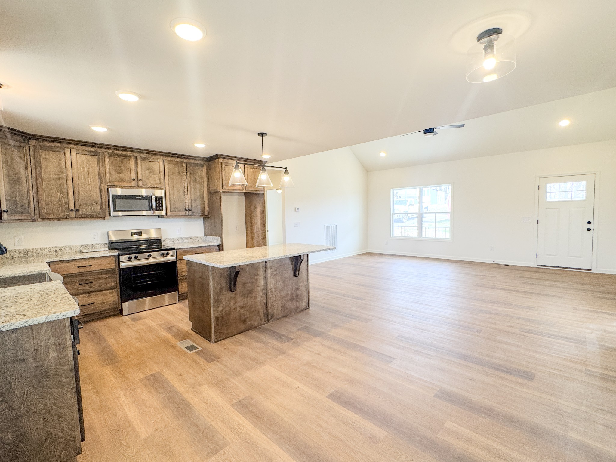 575 Pleasant Hill Road Lafayette, TN 37083 - Photo 9 of 51 a large kitchen with stainless steel appliances kitchen island granite countertop a stove a sink a refrigerator white cabinets and wooden floor