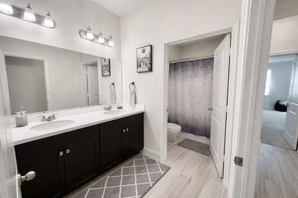 a spacious bathroom with a double vanity sink a toilet and a mirror