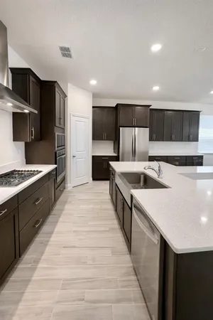 a large kitchen with stainless steel appliances kitchen island a sink dishwasher a stove and a refrigerator with wooden floor