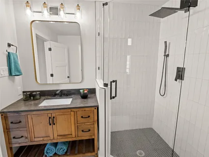 a bathroom with a sink a vanity a mirror and shower