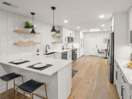 a kitchen with a sink a stove a refrigerator and chairs with wooden floor