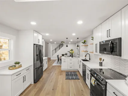 a kitchen with stainless steel appliances a stove a sink a refrigerator cabinets and a wooden floor