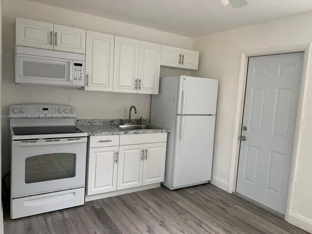 a kitchen with granite countertop white cabinets and white appliances